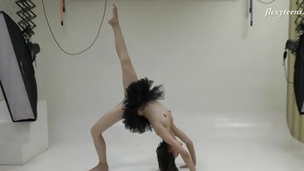 Ballerina in a black dress does standing splits